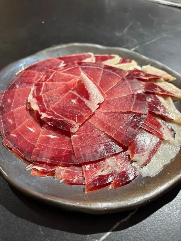 Jamón curado cortado en lonchas finas dispuesto en un plato.