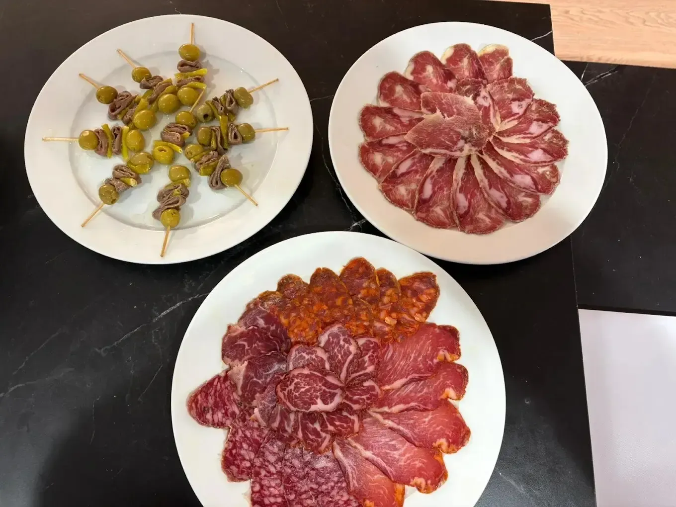 Tres platos con brochetas de fruta en forma de flor y fruta en rodajas dispuestas como aperitivos decorativos.