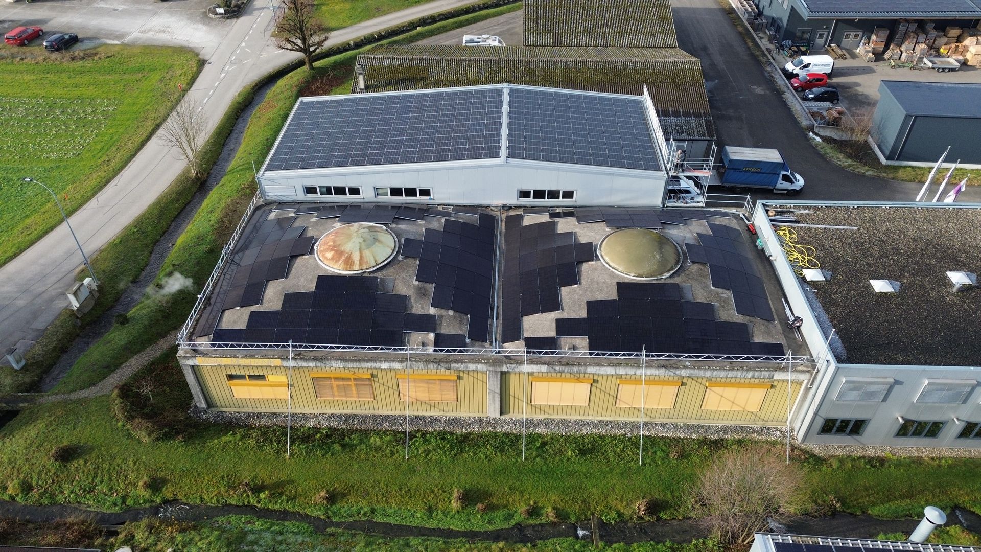 Eine Luftaufnahme eines Gebäudes mit Solarmodulen auf dem Dach.