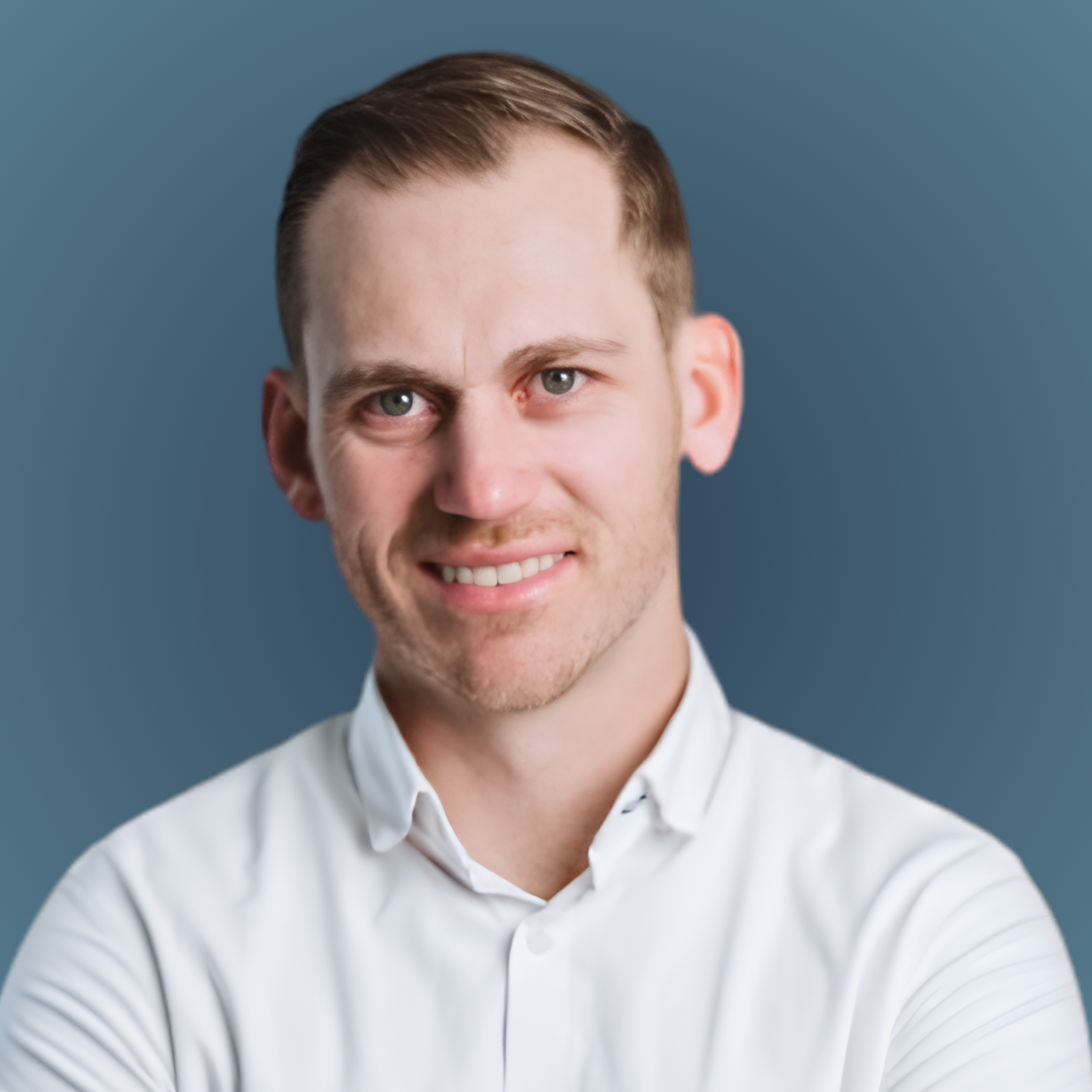Portrait of a smiling man in a white shirt against a blue-gray background