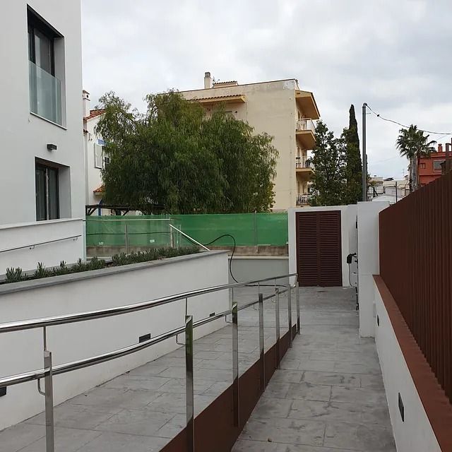 Una rampa que conduce a un edificio con una valla al fondo.