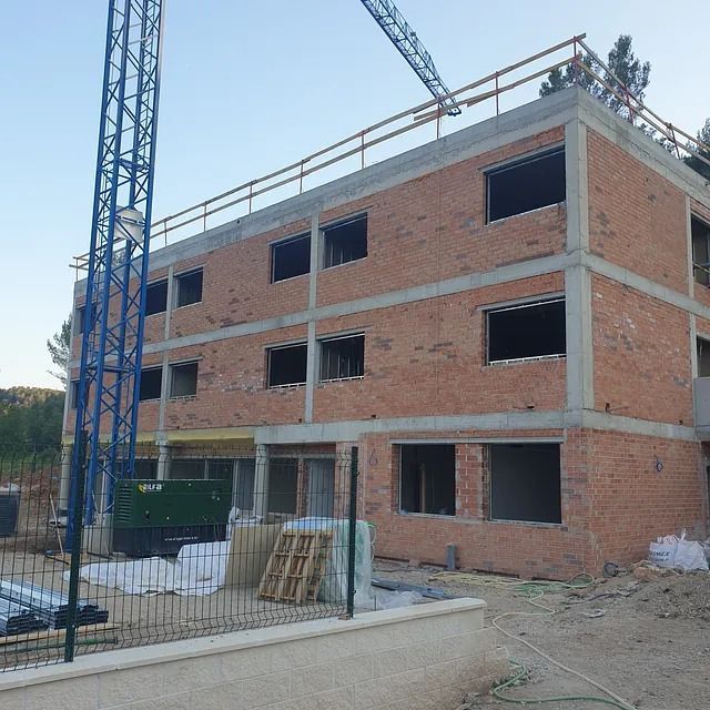 Un edificio de ladrillos en construcción con una grúa encima.