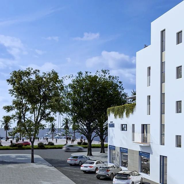 Un edificio blanco con coches aparcados delante.