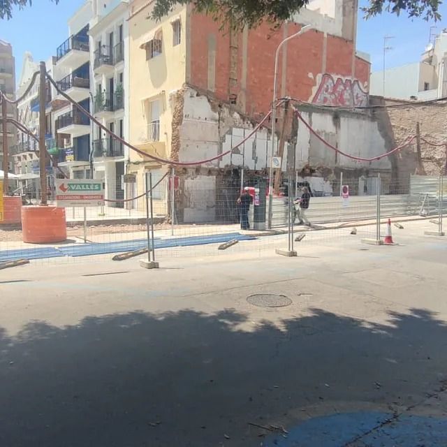 Un grupo de personas camina por una calle frente a un edificio con grafitis.