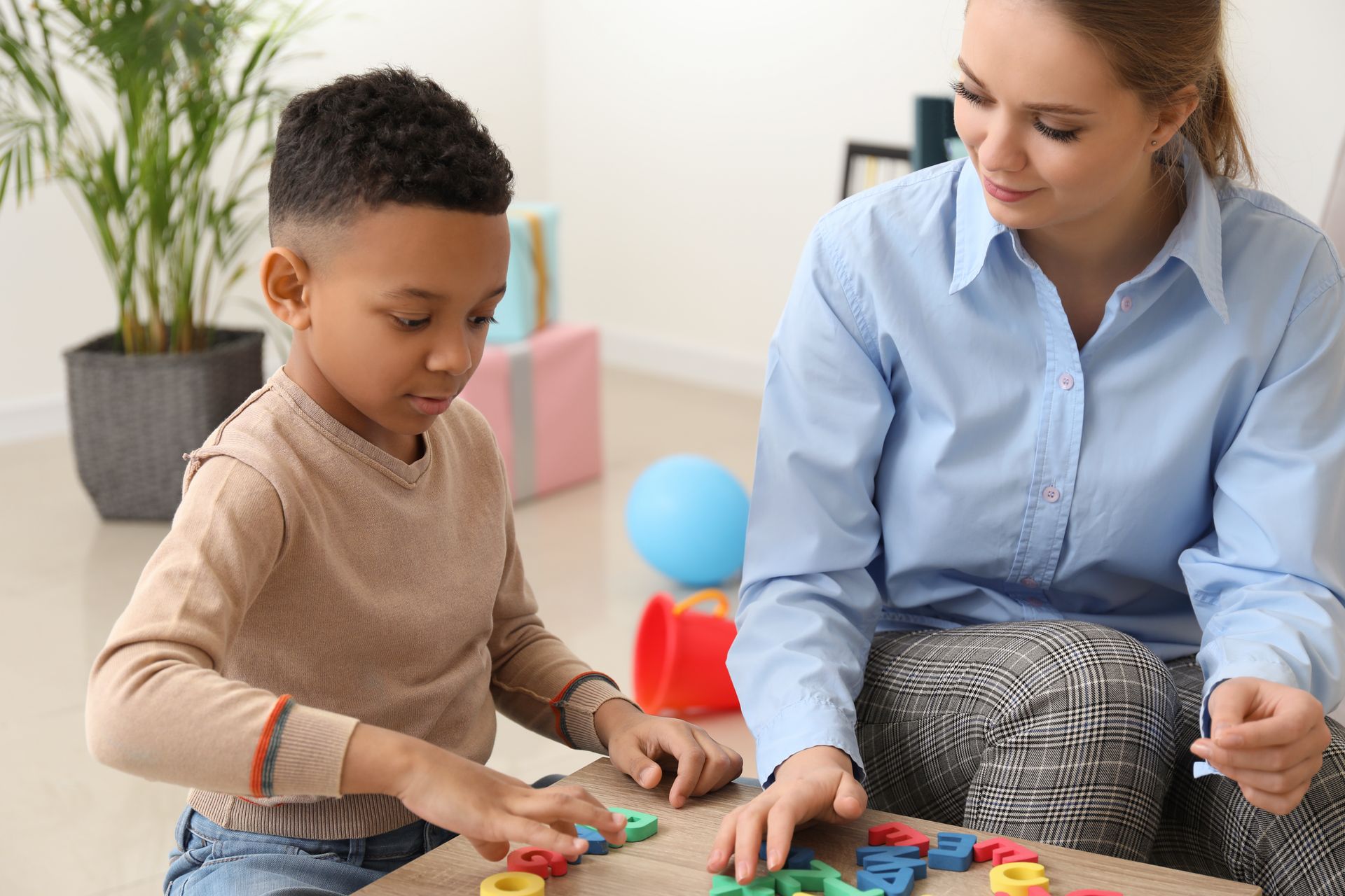 Un adulte et un enfant jouent avec des blocs colorés à une table à l'intérieur.