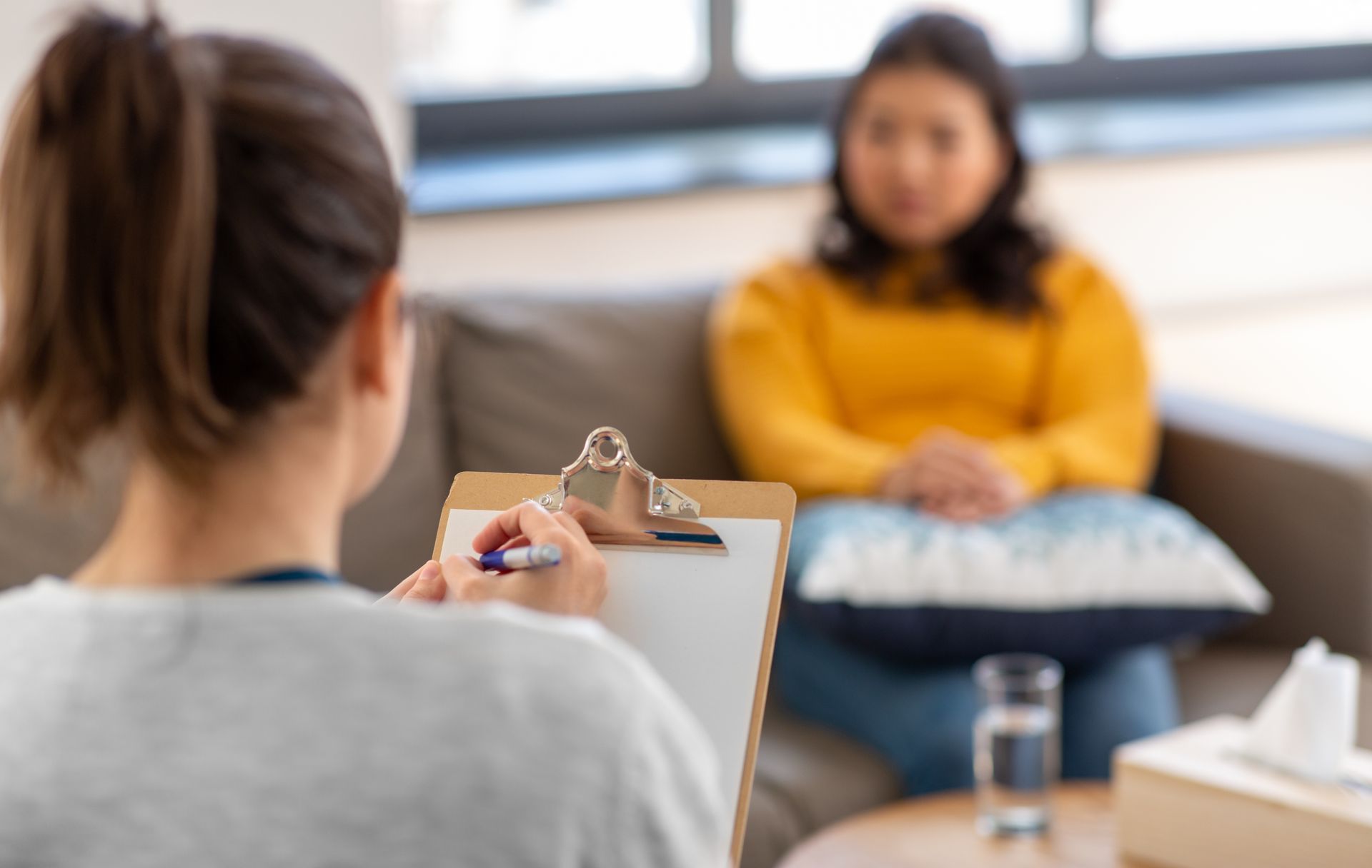 Un thérapeute prend des notes pendant qu'il parle avec un client assis, dans un cabinet de consultation.