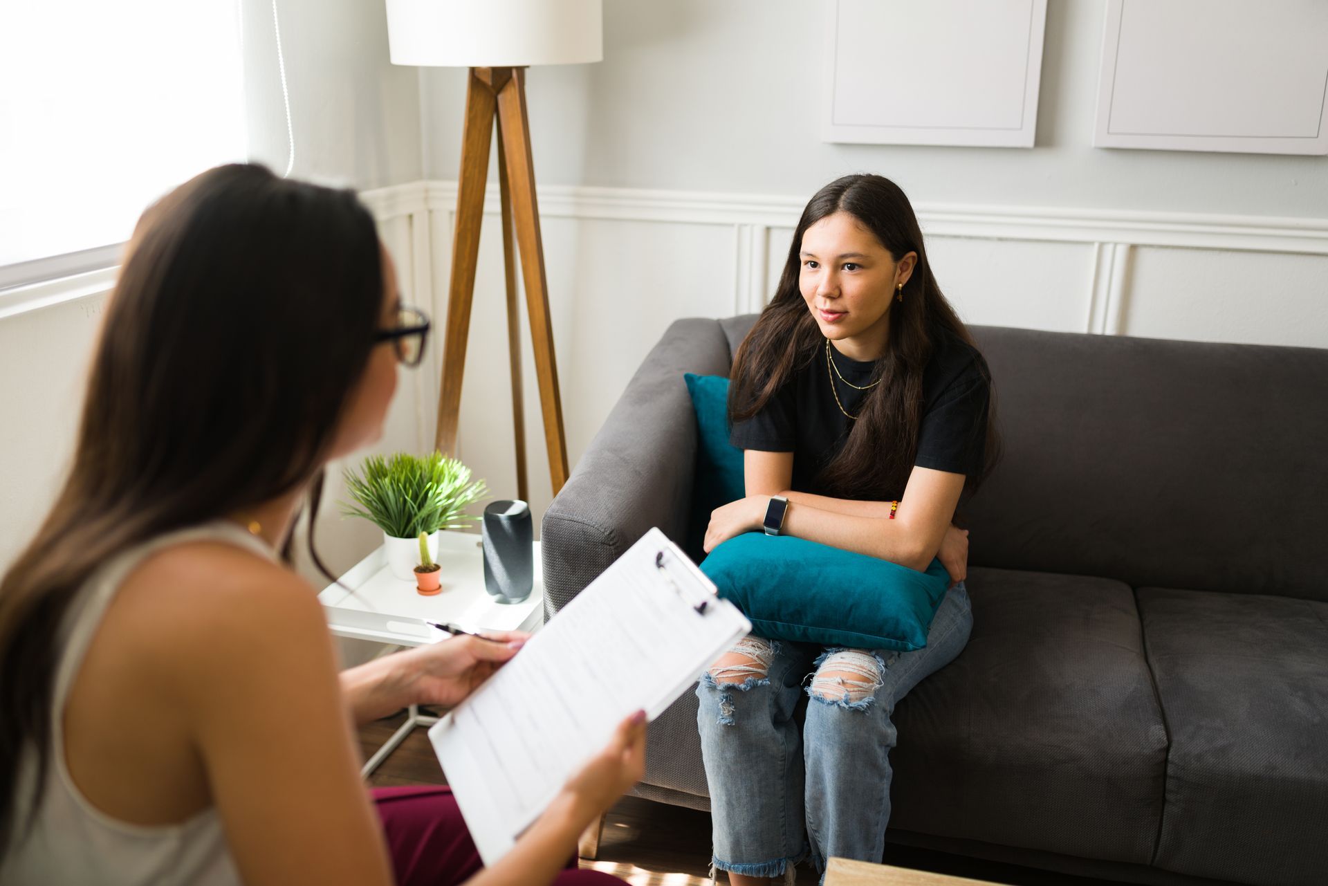 Un thérapeute parle avec un client sur un canapé dans un bureau lumineux faisant office de salon.