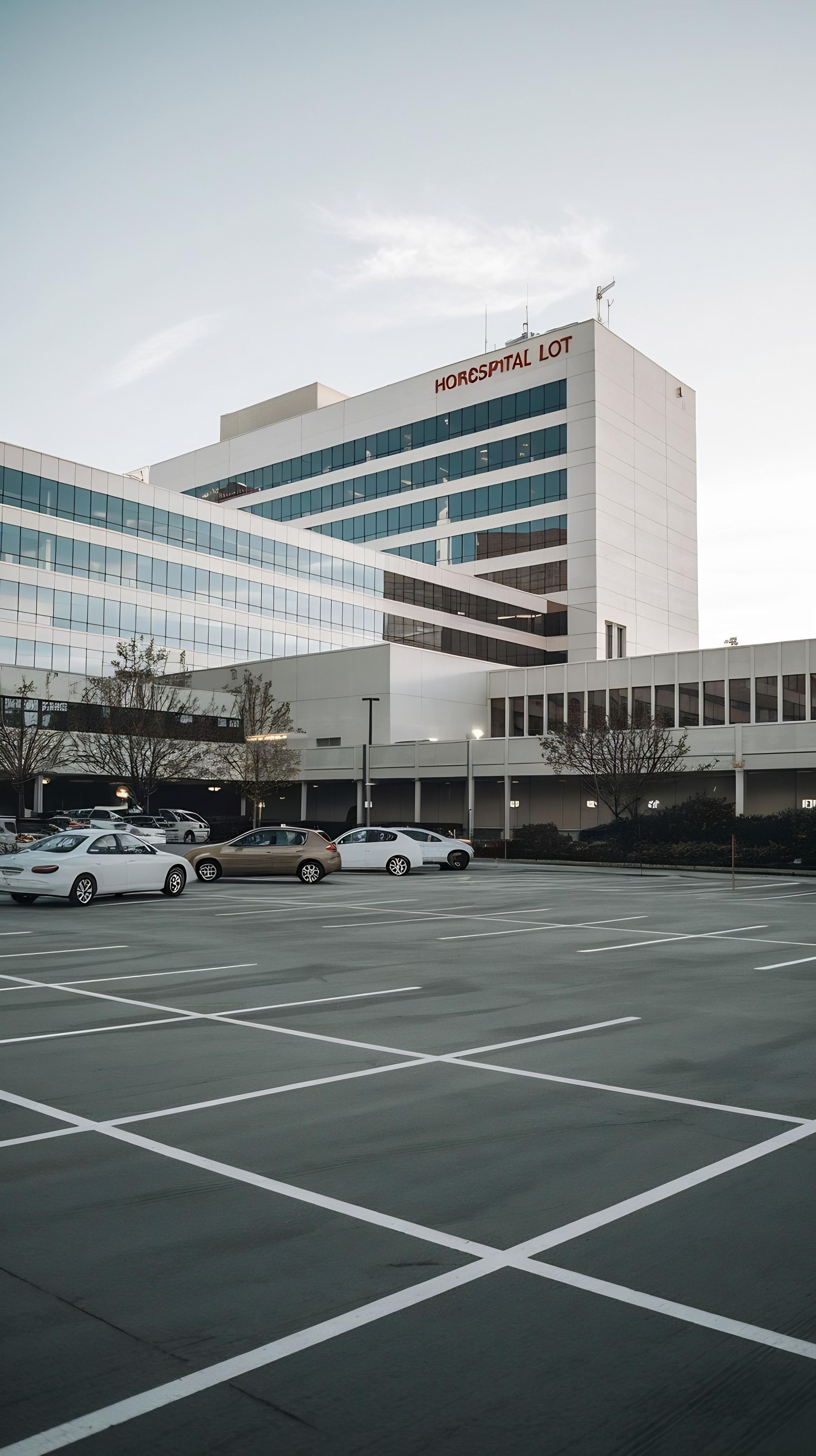 Immeuble de bureaux moderne avec un grand parking et des voitures garées sous un ciel couvert
