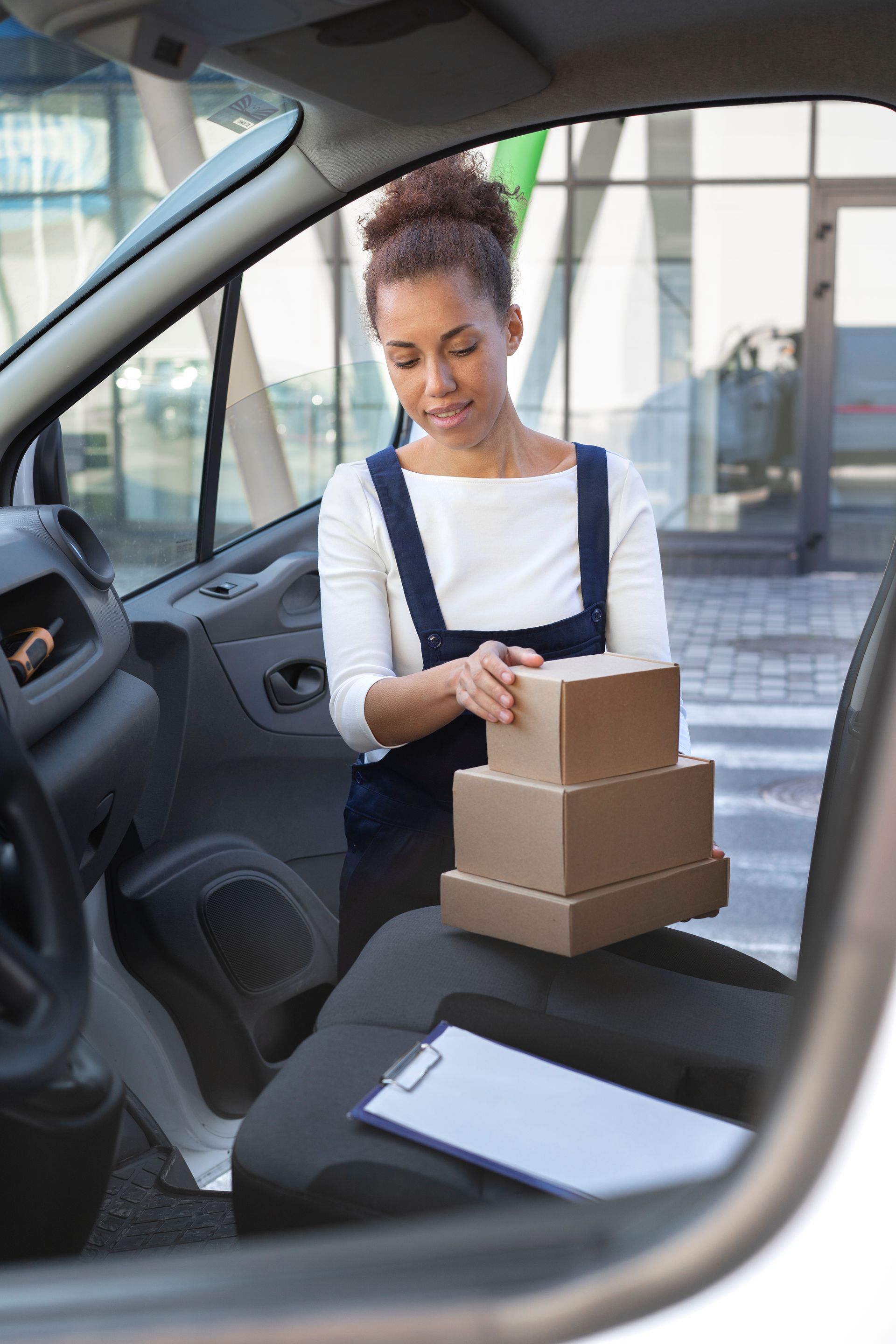 Une personne chargeait des cartons empilés dans une voiture par la portière ouverte.