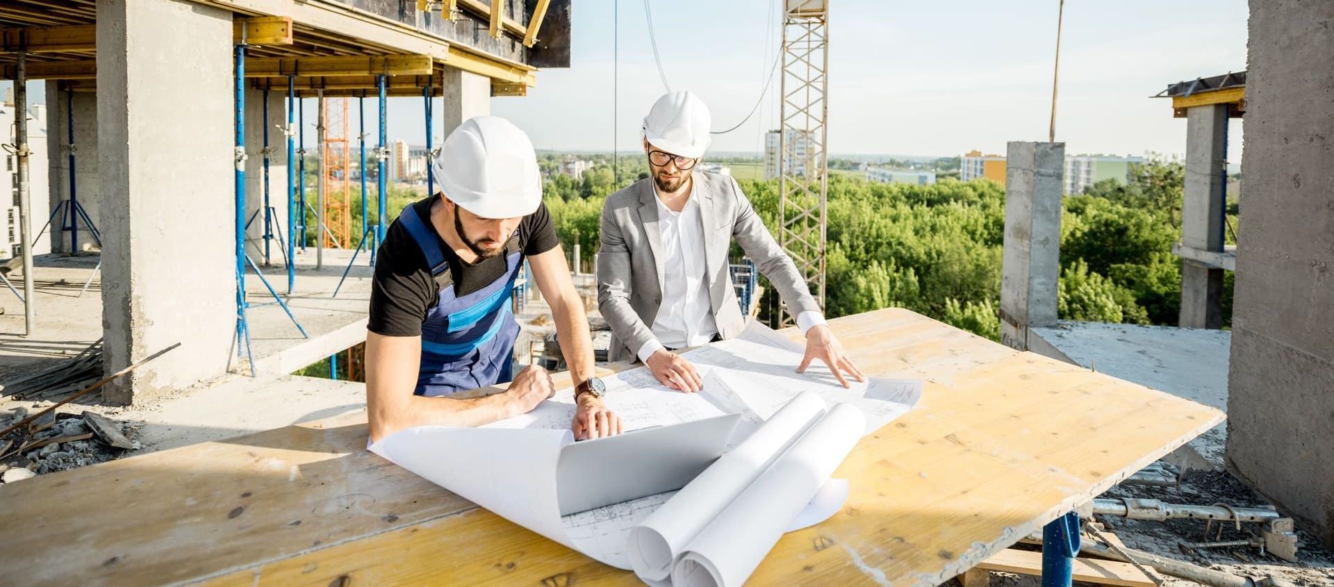 Zwei Männer arbeiten an einer Baustelle und schauen auf Zeichnungen | Ingenieurbüro B. Eng. D. Blattner
