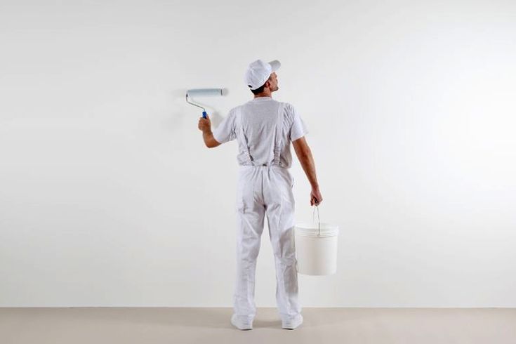 Photo d'un menuisier qui applique de la peinture sur une planche en bois