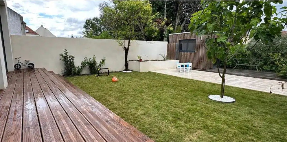Une terrasse en bois et deux arbres.