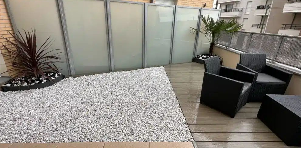 Une terrasse avec des fauteuils noirs.