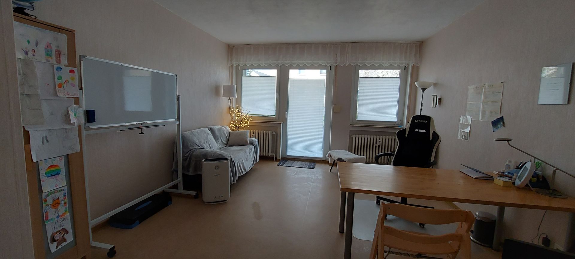 Ein Wohnzimmer mit Couch, Schreibtisch, Stuhl und Glasschiebetüren.