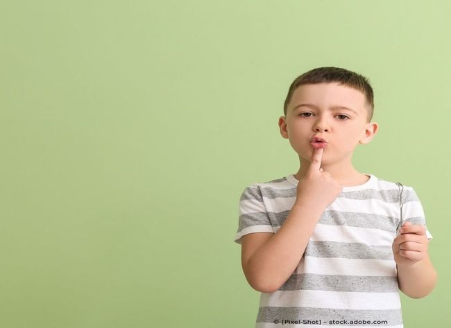 Ein kleiner Junge in einem gestreiften Hemd hält einen Lutscher im Mund.