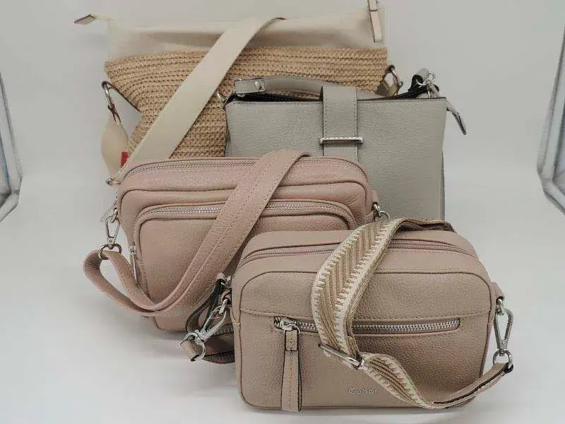 Drei beige und rosafarbene Handtaschen gestapelt auf einer weißen Fläche