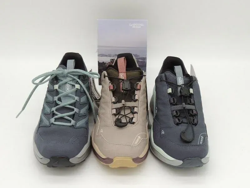Drei Wanderschuhe in Marineblau, Beige und Dunkelgrau vor weißem Hintergrund.