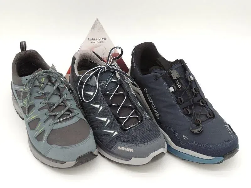 Drei graue und marineblaue Wanderschuhe vor weißem Hintergrund