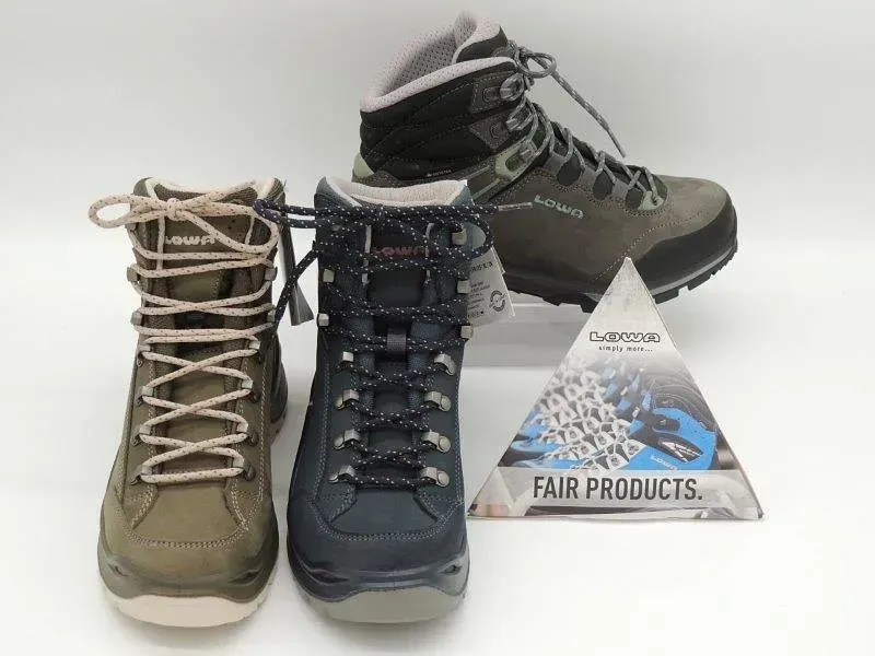 Drei Wanderschuhe und eine Verpackung von Fair Trade Products auf weißem Hintergrund