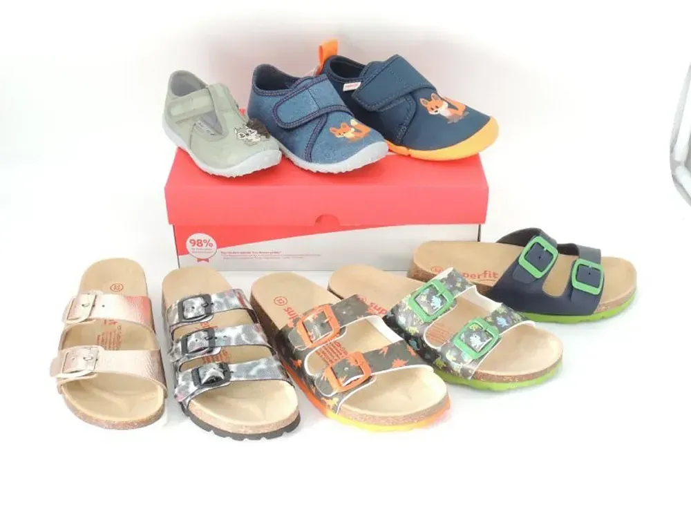 Verschiedene Kindersandalen und -schuhe in Blau, Grün, Beige und Silber, präsentiert auf Kartons.