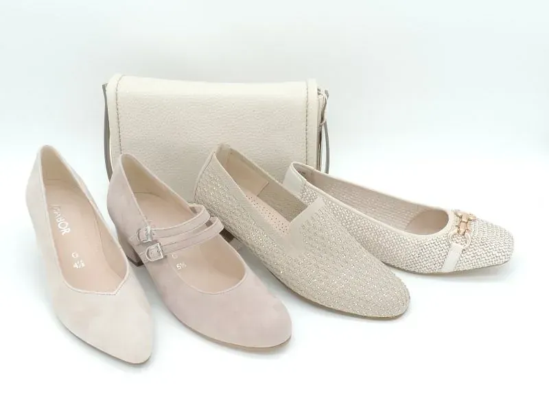 Drei Paar cremefarbene und rosafarbene Damen-Ballerinas, ausgestellt vor einer passenden Handtasche.