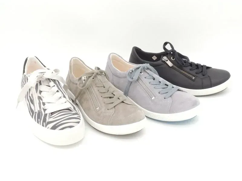 Vier lässige Sneaker in Weiß, Beige, Hellgrau und Dunkelgrau auf weißem Hintergrund