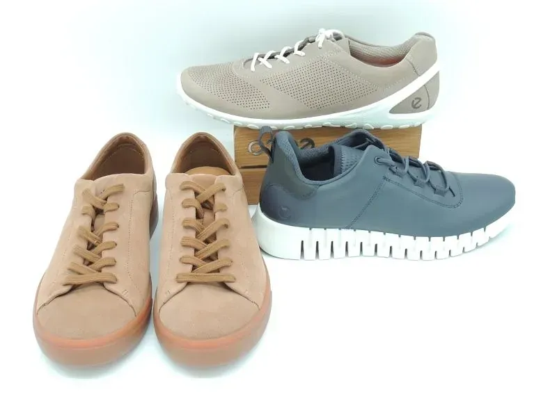 Drei Paar lässige Sneaker in Hellbraun, Beige und Blau auf weißem Hintergrund