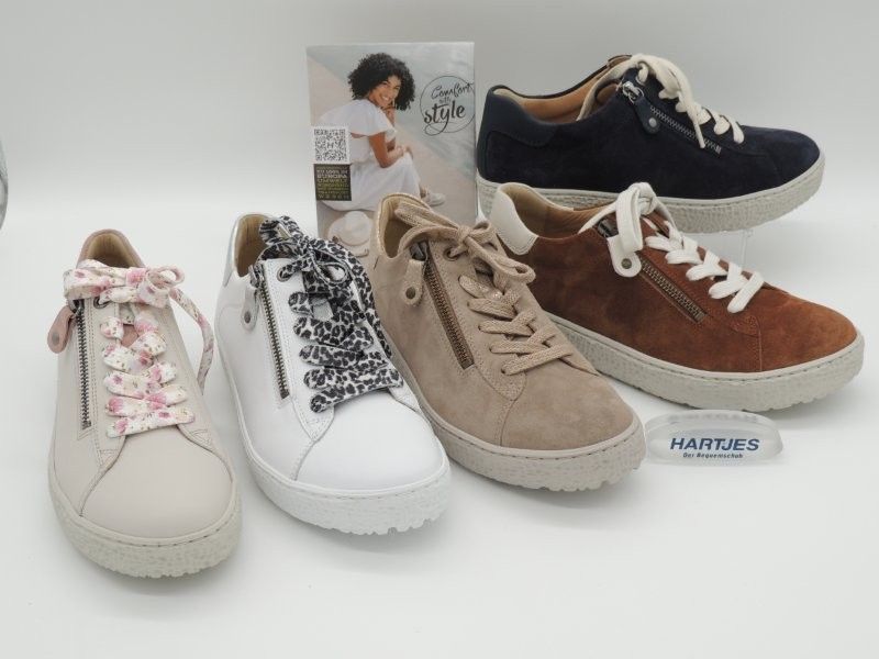 Vier lässige Sneaker in Beige, Weiß, Braun und Schwarz auf schlichtem weißem Hintergrund.