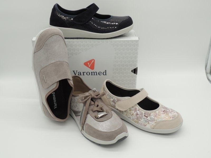 Vier orthopädische Schuhe von Varomed in Schwarz, Beige und mit Blumenmuster auf einer Produktverpackung.