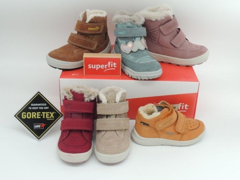 Kinderwinterstiefel in Rosa, Beige, Blau und Orange, gestapelt auf einem Superfit-Karton mit Gore-Tex-Logo
