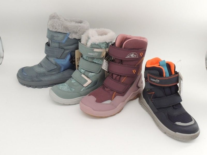 Vier Winterstiefel in Blau, Türkis, Rosa und Dunkelgrau vor einem weißen Hintergrund