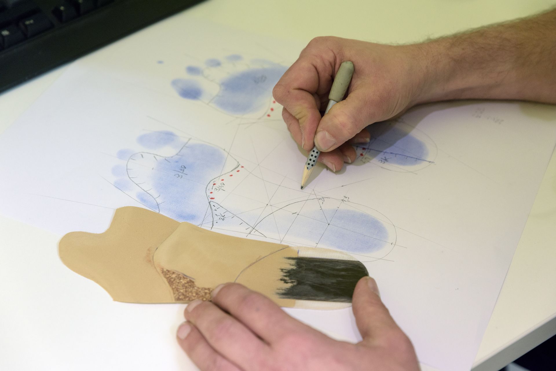 Hände skizzieren eine Aktfigur auf Papier mit blauen Aquarellfarben und Bleistiftlinien
