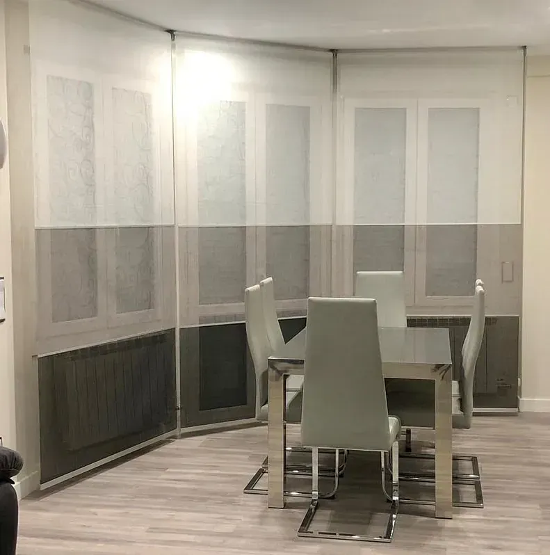 Un comedor con mesa y sillas y persianas en las ventanas.