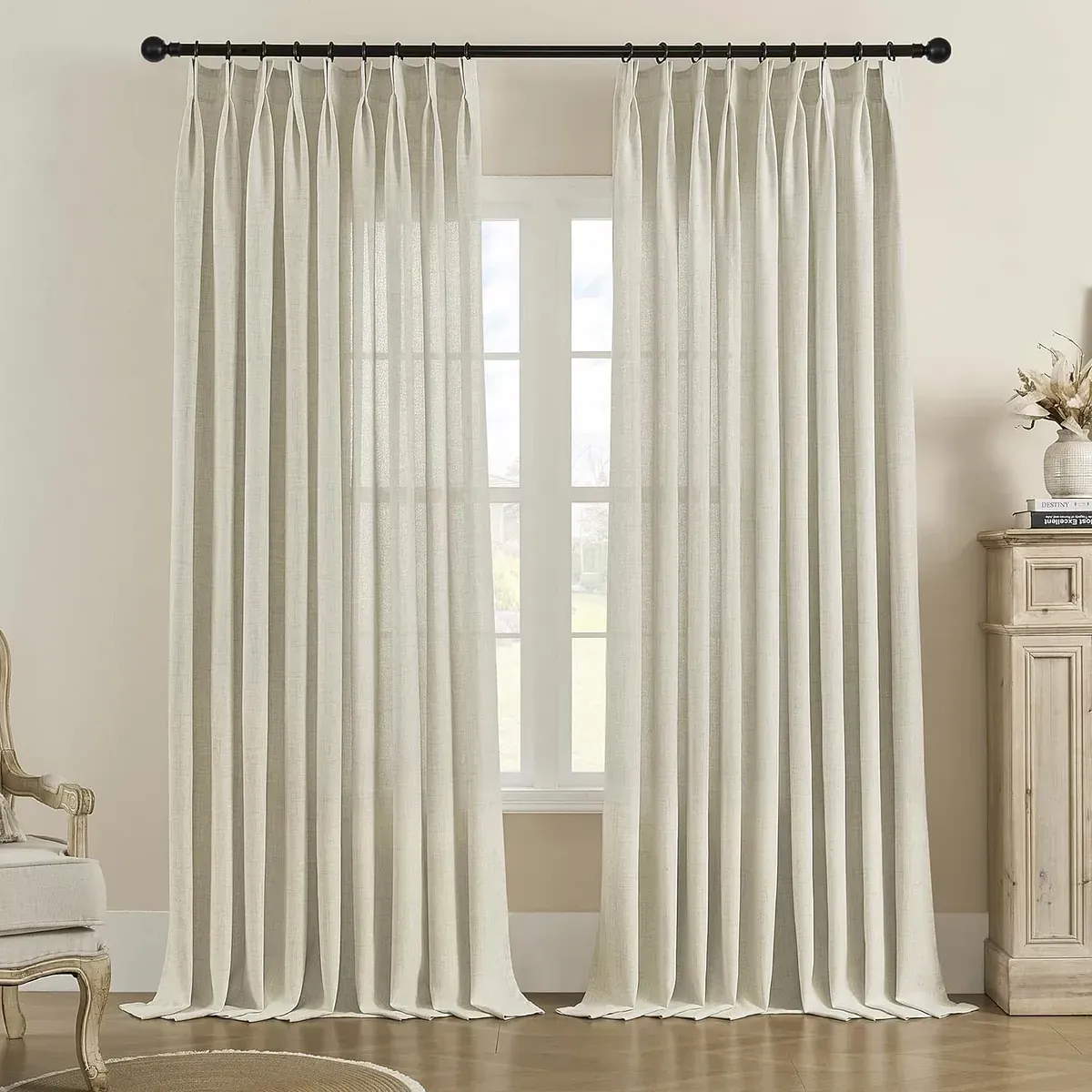 Un par de cortinas blancas cuelgan de una ventana en una sala de estar.