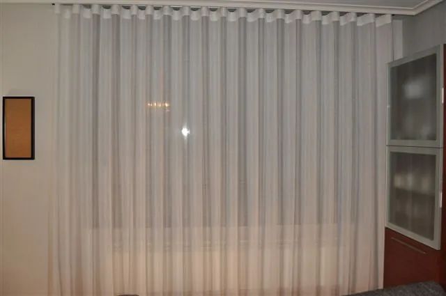Una cortina blanca cuelga de una ventana en una sala de estar.