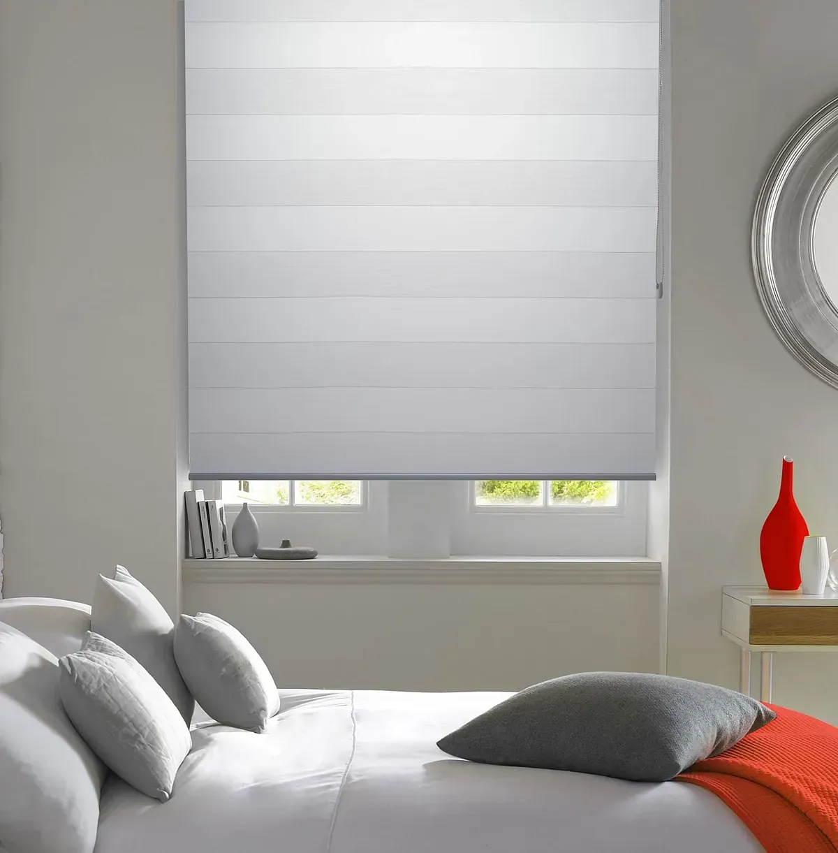 Un dormitorio con una cama y una ventana con persiana blanca.