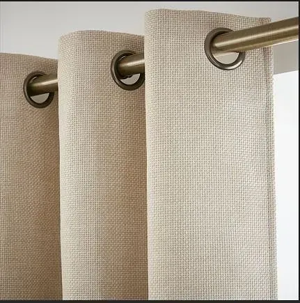 Un primer plano de un par de cortinas beige colgadas en una ventana.
