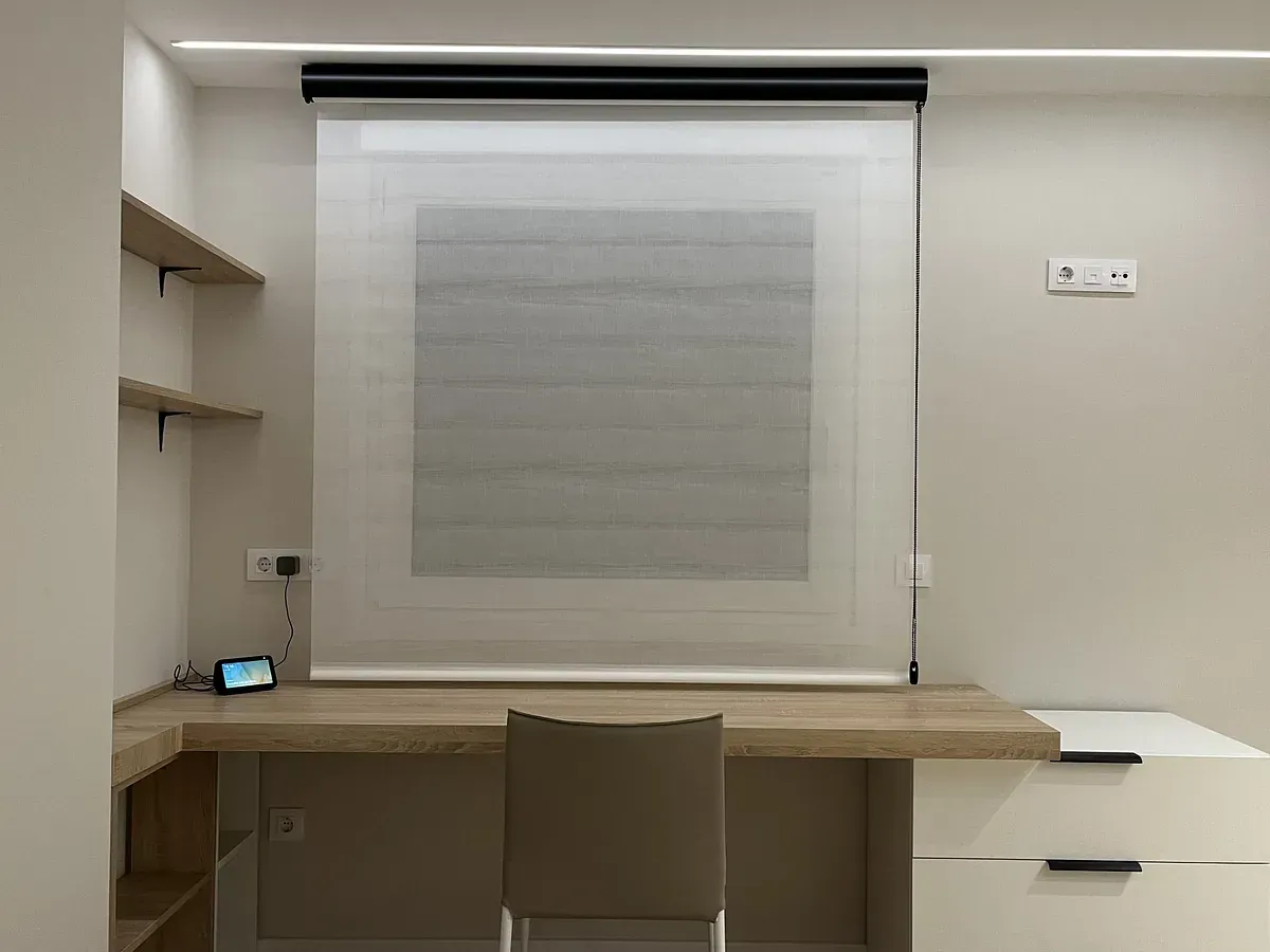 Un escritorio con una silla y una ventana con una persiana.