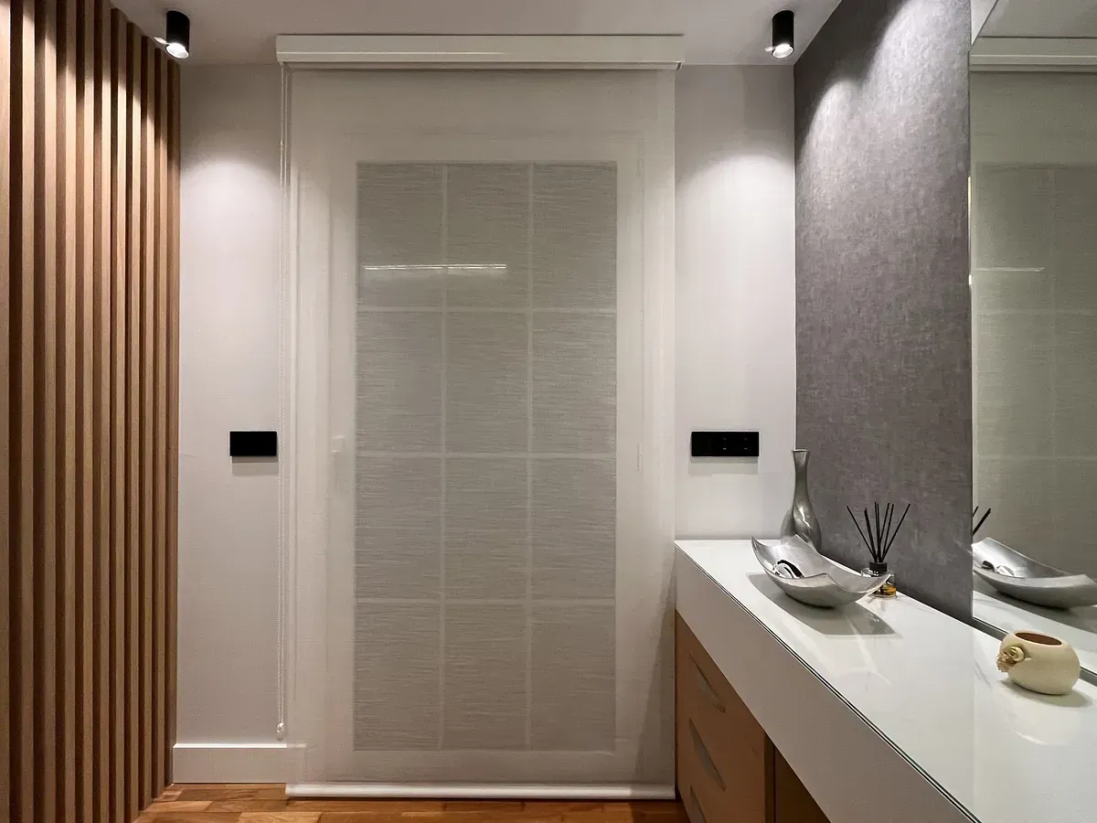 Un pasillo con una puerta corrediza de vidrio y un espejo.