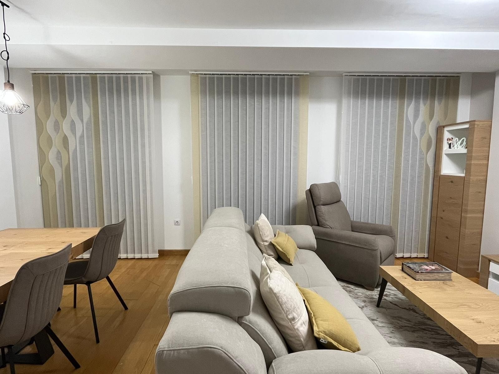 Una sala de estar con sofá, silla, mesa y cortinas.