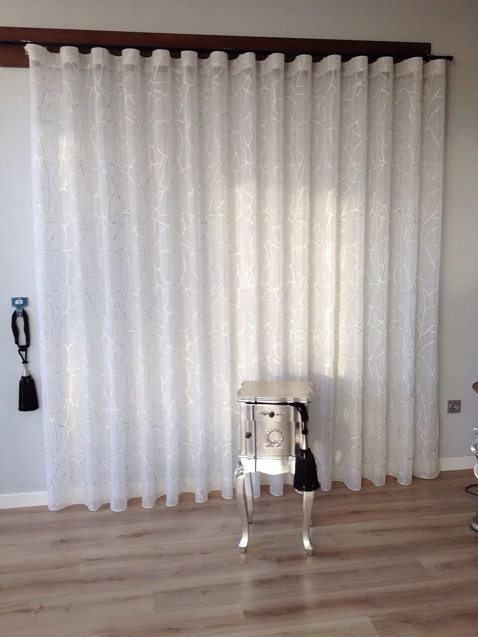 Una habitación con cortinas blancas y una mesa pequeña.