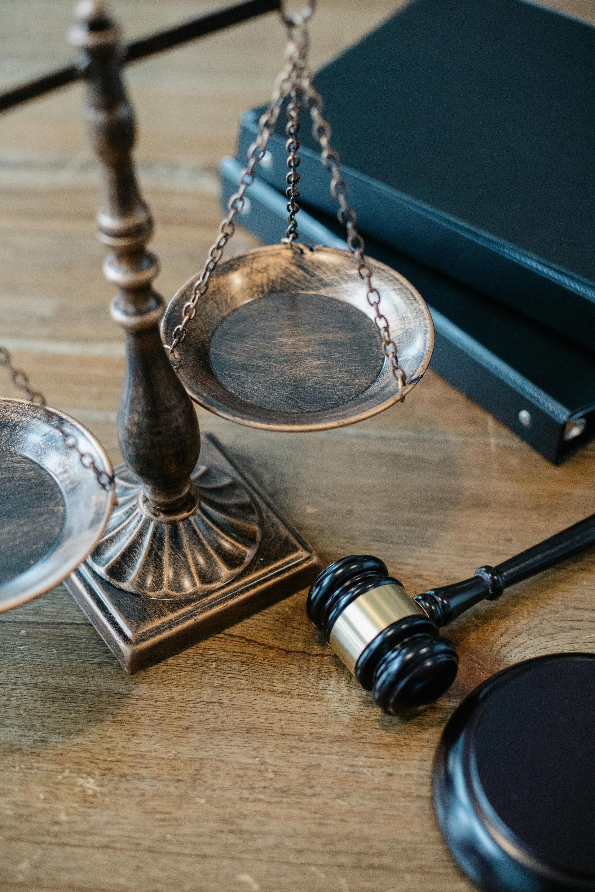Balanza de la justicia y mazo sobre una mesa de madera, junto a dos libros oscuros.