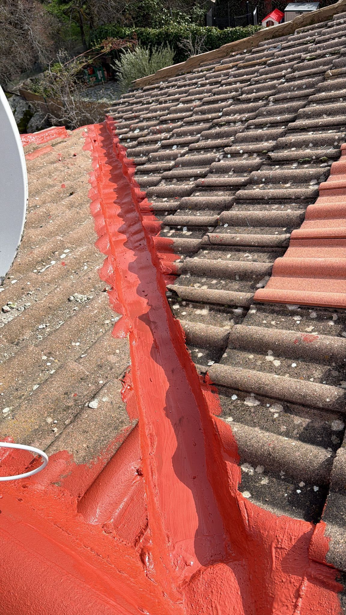La cumbrera del tejado está cubierta con sellador rojo entre tejas de terracota desgastadas.