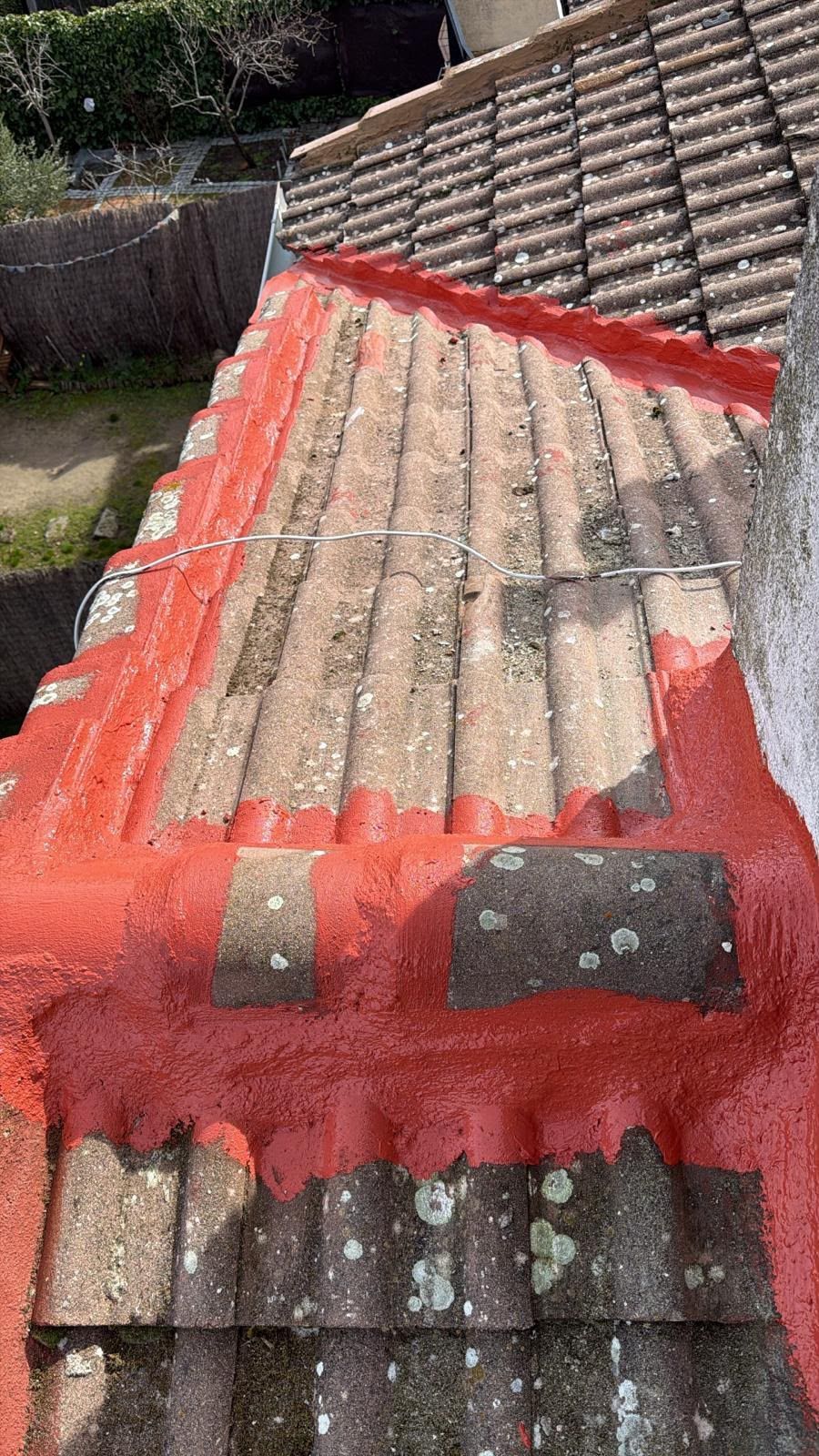 Azotea con parches de impermeabilización rojos sobre un antiguo tejado de tejas, vista desde arriba.