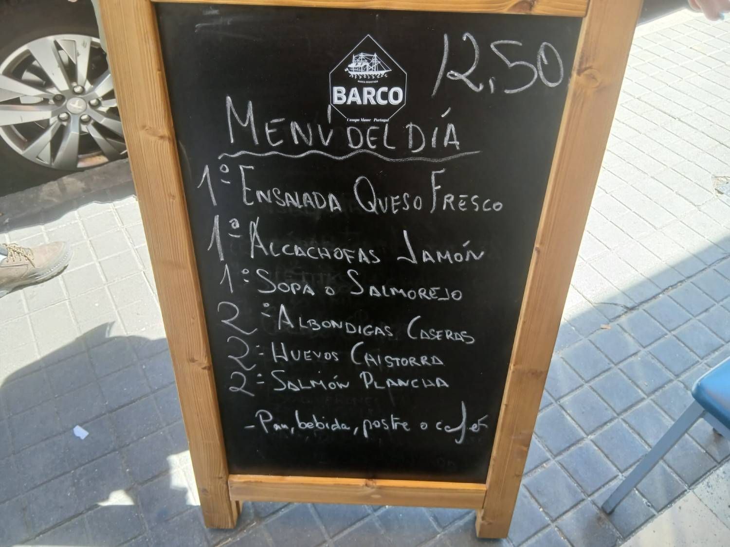 Cartel de pizarra con el menú de la cafetería en la acera, con el precio escrito en la parte superior.
