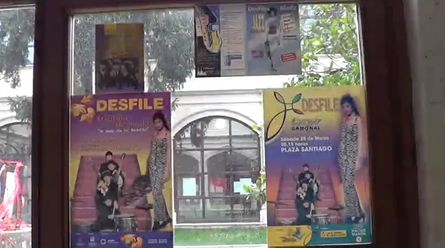 Carteles en una ventana anunciando un desfile de moda con una modelo posando frente a un edificio arqueado.