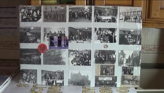 Tablero con fotos antiguas en blanco y negro, probablemente de una reunión o evento histórico. Cubierto con film transparente.