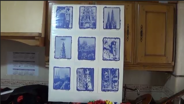 Obra de arte en azul y blanco de nueve paisajes urbanos exhibidos sobre un fondo de cocina.