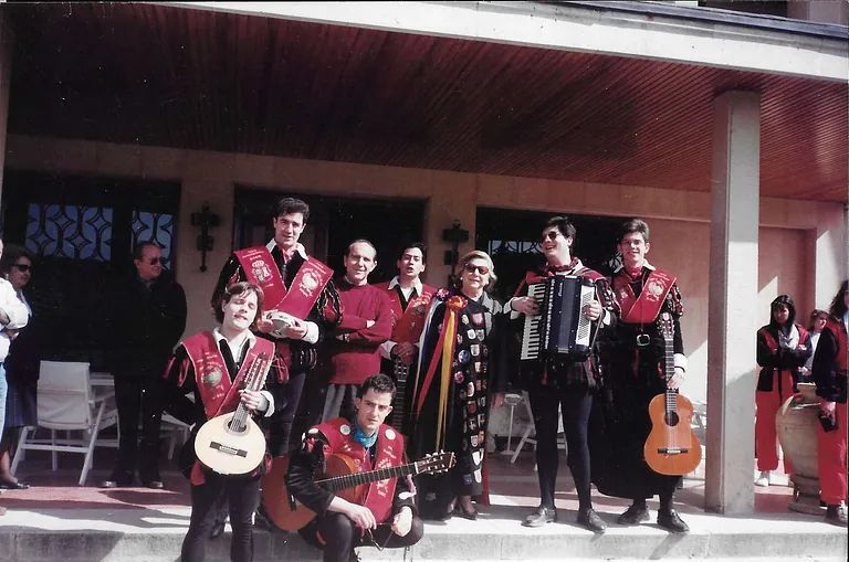 Un grupo de músicos vestidos con atuendos medievales posan frente a un edificio, algunos sosteniendo instrumentos.