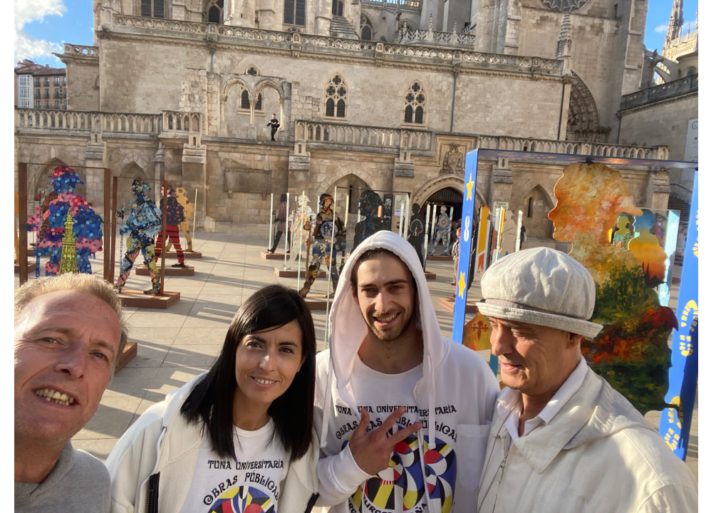 Cuatro personas posan para una selfi frente a una catedral. Están rodeadas de esculturas artísticas.